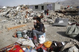 中國青海玉樹縣發生7.1級地震第五日，一名災民坐在倒塌的房子前。（圖：美聯社） <br/>