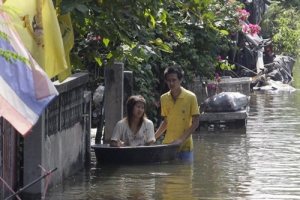 曼谷市區25日開始有水浸的情況，圖為一對夫妻在淹水的街上。（圖：美聯社） <br/>