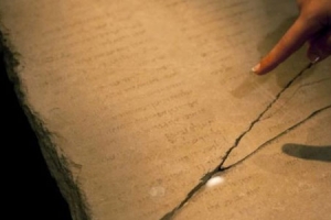 耶路撒冷博物館的一名工作人員用手指著加百列石板，上面寫著神秘的希伯來文並提到了天使長加百列。（圖：新浪） <br/>