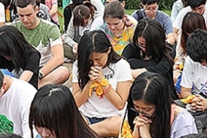 東海大學生坐在草地上在校牧的帶領下一起禱告。（圖：網絡截屏） <br/>