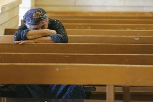 因ISIS迫害而逃離家園的基督徒在教堂內禱告。（圖：法新社） <br/>