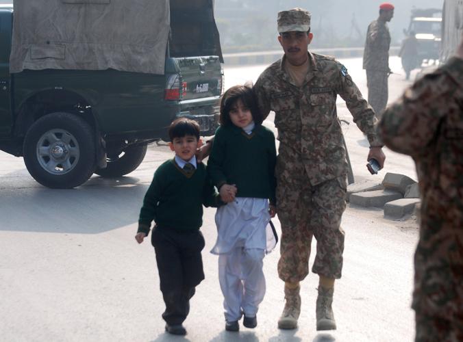 巴基斯坦西北部白沙瓦市一所公立學校16日早上被塔利班武裝分子襲擊，巴基斯坦士兵把學童救出。(圖:路透社)