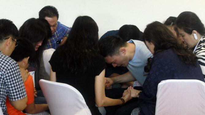 亞航失聯航班QZ8501乘客的家屬在等候消息的時候，聚集在一起禱告。(圖:美聯社)