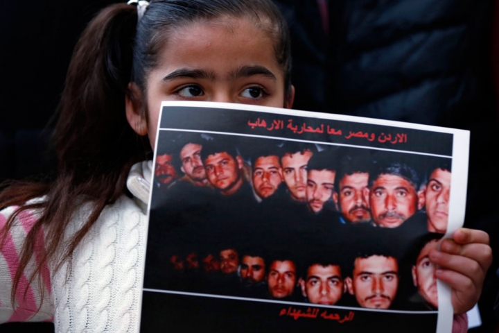 在埃及大使館前的集會中，一名女孩手持21名埃及基督徒被ISIS斬首的照片。(圖: Christian News)