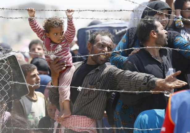 一名敘利亞男子抱著女兒在土耳其的邊界請求過境避難。(路透社)
