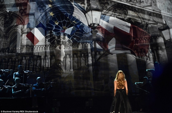在她身後的大型螢幕播出映著紅、白、藍三色法國巴黎鐵塔的影像，以及巴黎都巿人們在恐襲後，被深深的哀傷氣氛所籠罩的各種生活場景。