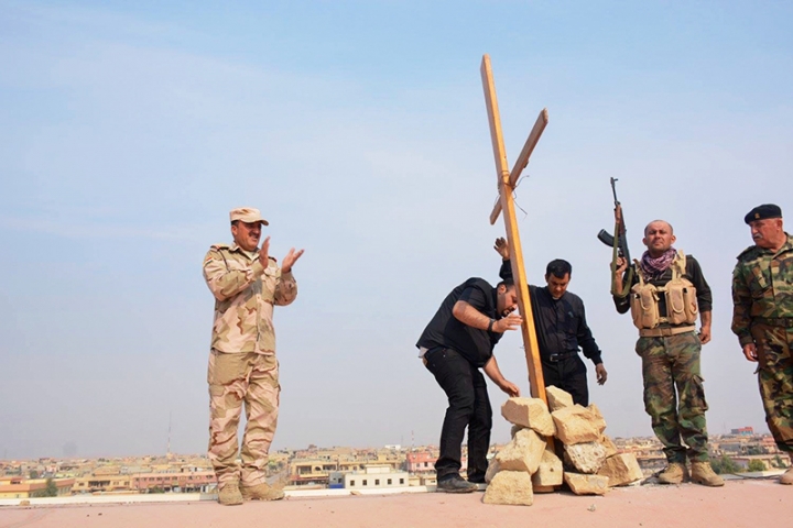 兩名伊拉克牧者在士兵的幫助下把十字架重新擺在克拉克斯的最大教堂Tahira教堂上。(圖：Open Doors)