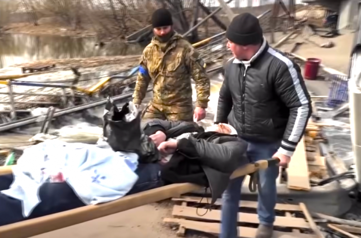 烏克蘭基輔州伊爾平市，有人用擔架把死傷者抬出。（圖：Sky News視頻擷圖） 