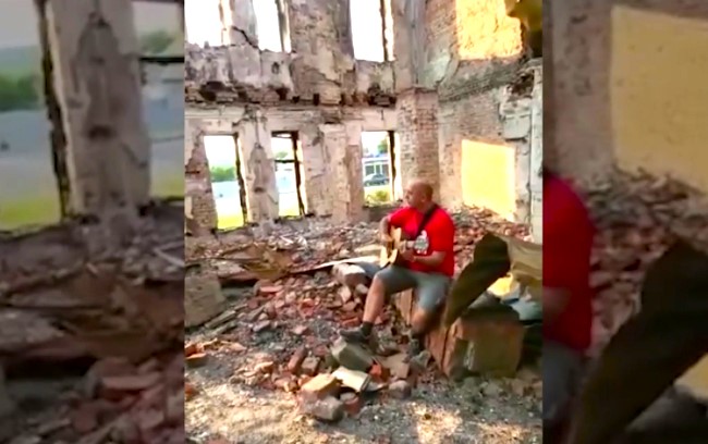 一名波蘭弟兄8月到遭俄軍炮轟的哈爾科夫［Kharkiv］贈送救援物資，並坐在瓦礫上獨唱詩歌。（圖： Release International facebook） 